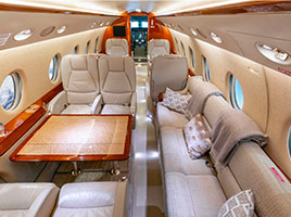 Interior of Gulfstream G200 jet with leather seats and leather bench with square wooden table 