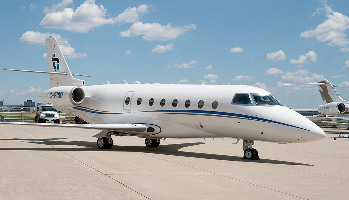 Exterior image of THI Gulfstream G200 jet with THI logo on tail at airport